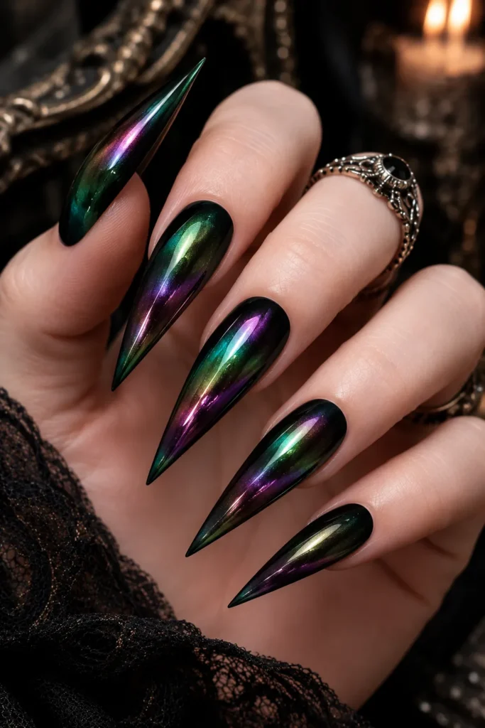 18. Iridescent Black Beetle-Shell Nails

This design proves you don’t need nail art to achieve a witchy effect. A black base combined with oil-slick chrome shifts between green, purple, and bronze as the hands move.

Best for: Nightlife, statement manicures, and anyone who dislikes detailed nail art.
Nail shape: Any.
Length: Any.
Finish: Iridescent chrome.
Skill level: Beginner.
Tools/products: Black gel, aurora or oil-slick chrome powder, no-wipe top coat, applicator, final top coat.
How to Create It
Apply two coats of black gel.
Add and cure a no-wipe top coat.
Buff aurora chrome powder across the nail.
Continue until the surface becomes highly reflective.
Dust away excess and seal thoroughly.

Drying/curing time: Approximately 60 seconds per layer.

Lasts: Around 3 weeks.

Aftercare tip: Refresh the top coat around the middle of the wear period to preserve the color shift.

Common mistake: Using only one thin sealing layer, allowing the chrome to wear away at the edges.